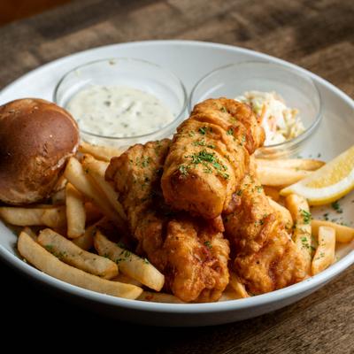 Fish and chips served with a soft roll, coleslaw, tartar, and a lemon wedge.