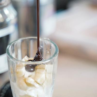 adding hot fudge to coed sundae.