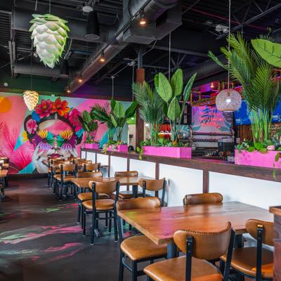 Interor with pink accents, large plants, and mural of a woman with a floral headdress.