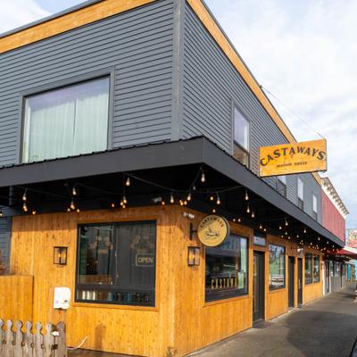 Exterior with light wood, string lights, entrance and a sign.