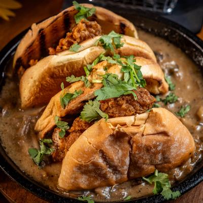 Crispy chicken sandwiches topped with cilantro in creamy gravy.