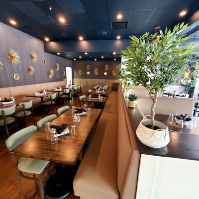 Interior featuring dining tables with chairs, and an ornamental potted tree on a counter.