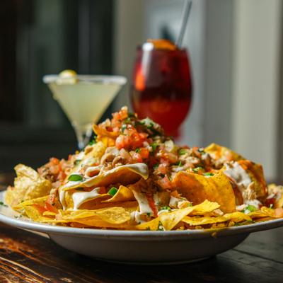 Buffalo bleu chicken nachos topped with sauce and herbs.