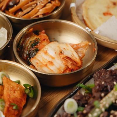 Bulgogi platter with various sides and condiments served in brass bowls, close-up.