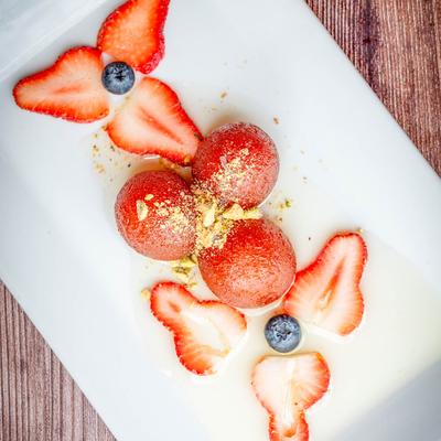 Warm cream dumplings dipped in rose water syrup, garnished with berries and crushed pistachios.