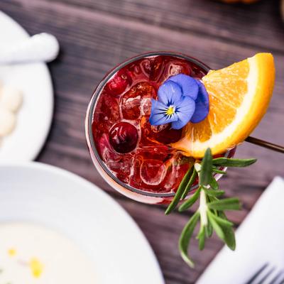Overhead view of the cocktail garnisged with orange slice, rosemary and a flower.