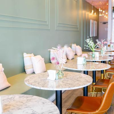 Interior, banquette bench with small pillows, marble top tables with leather padded chairs.