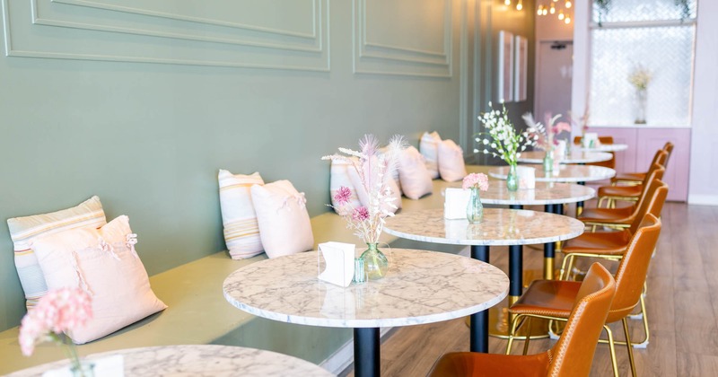 Interior, banquette bench with small pillows, marble top tables with leather padded chairs