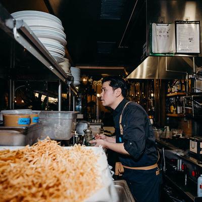 Chef working in the kitchen surrounded by fried snacks.