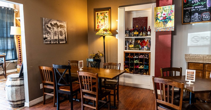 Cozy dining room with wooden furniture, colorful art, a wine-bottle display, and a floor lamp