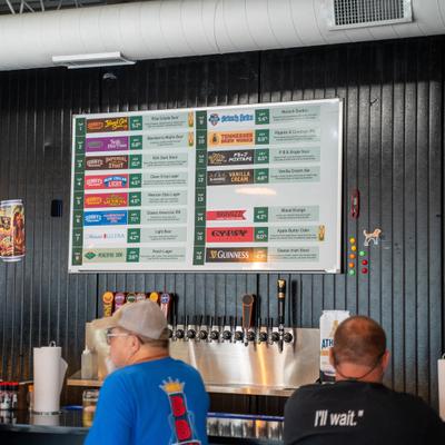 Beer tap wall with a beer menu above it.