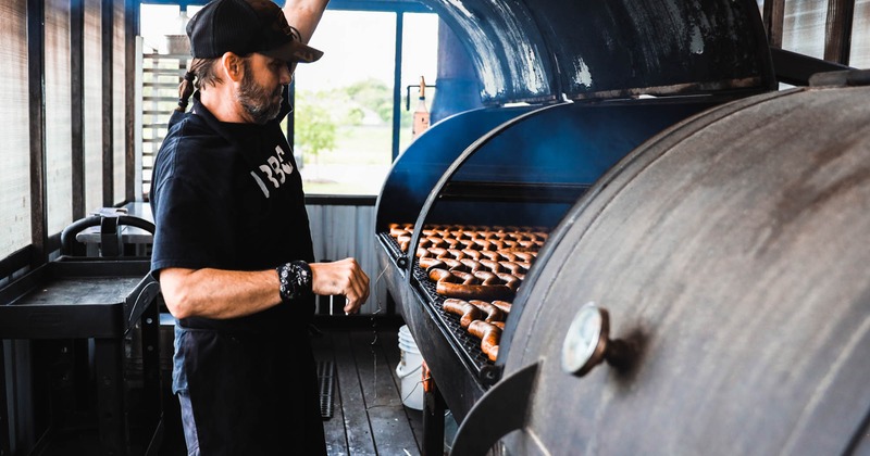 Employee smoking sausages in the smoker