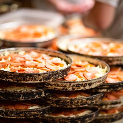 Kitchen, piled up baking plates with pizzas ready to get baked