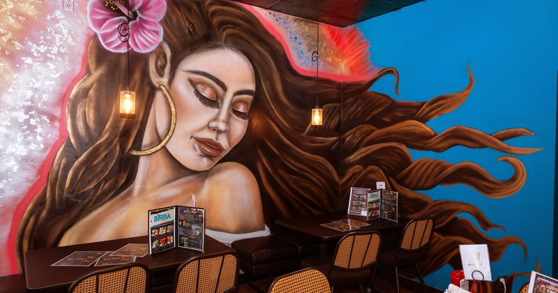 Dining tables along the wall with a large mural of a woman