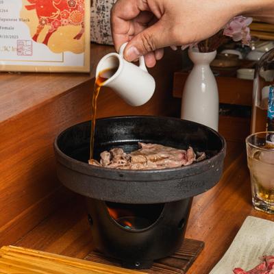 Person preparing a Japanese hot pot dish on the table.