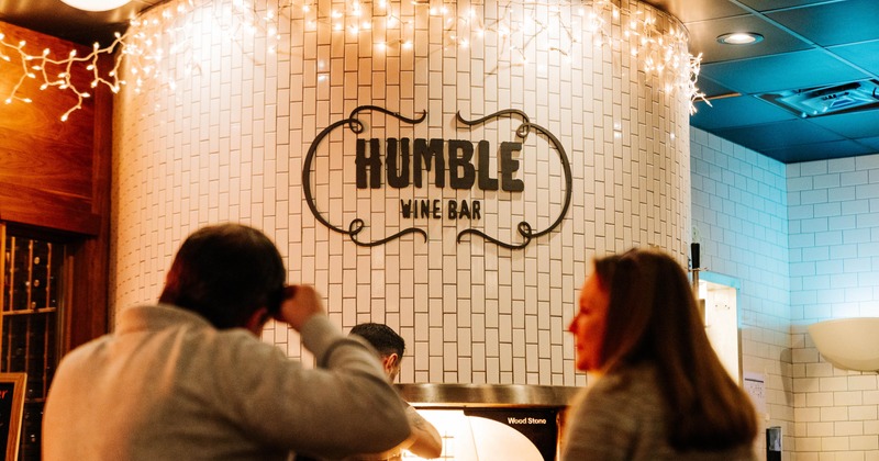 The interior featuring  a white subway tile wall with the bar's name