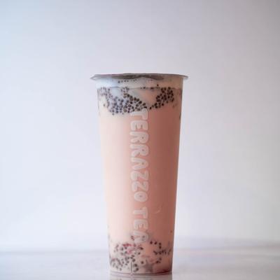 A tall, clear cup filled with pink bubble tea, featuring black seeds and a light foam on top.