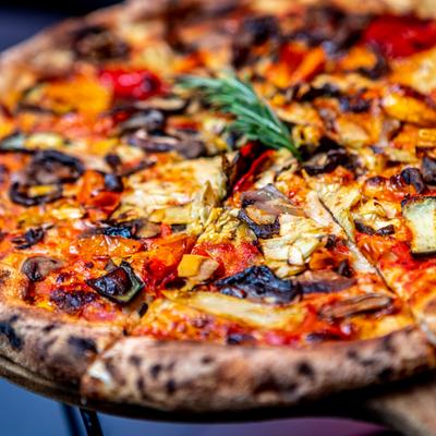 Vegan pizza, with tomato sauce, zucchini, eggplant, artichoke, and mushrooms.