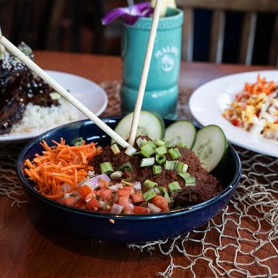 Barbacoa bowl with rice placed on a table with other dishes and a drink.