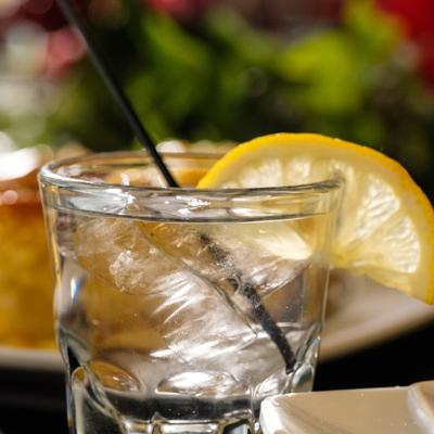 Clear iced drink in a rocks glass, garnished with a slice of lemon.