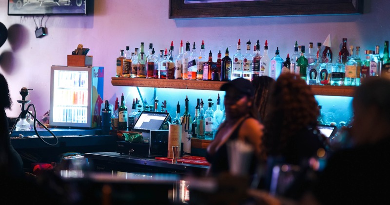 Dimly lit bar interior featuring a well-stocked liquor shelf