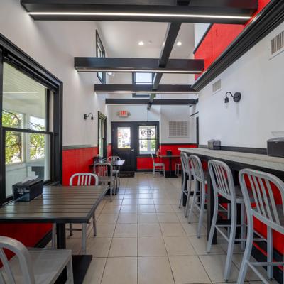 Interior with a red-and-white lower wall, tile floors, and a long counter and table seating.