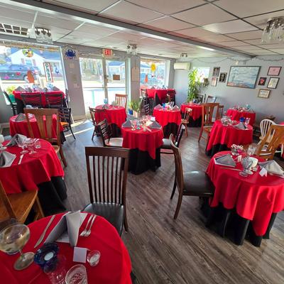 Bright interior with vibrant red tablecloths, elegant table settings, and large windows.