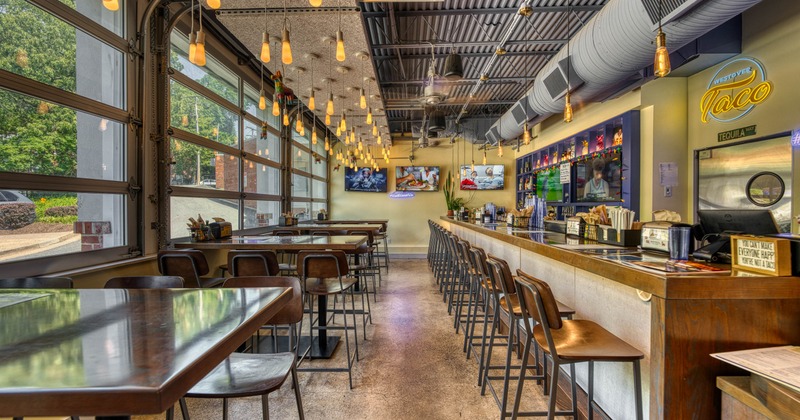 A modern interior - high tables, stools, glass doors, pendant lights and a long bar counter.
