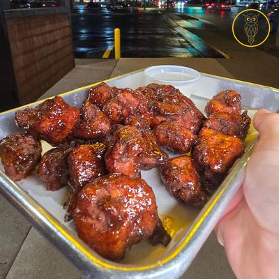 Hand holding a plate with chicken chunks.