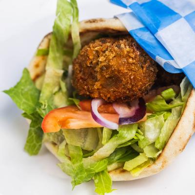 Pita wrap with falafel, lettuce, tomato, and red onion.