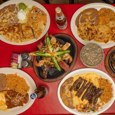 Mexican food spread featuring molcajete, quesadilla, enchiladas, and traditional sides.