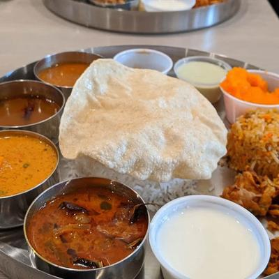 Indian thali with curries, rice, papadum, yogurt, and sides.