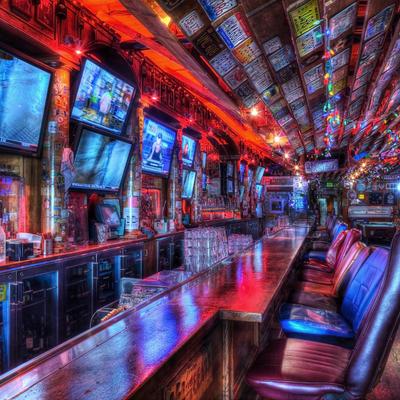 Vibrant bar scene with a long counter and colorful bar stools, numerous TVs and neon lights