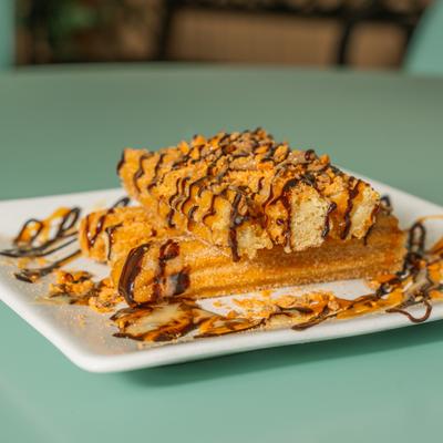 Stacked churros drizzled with chocolate and caramel sauces on a white plate.