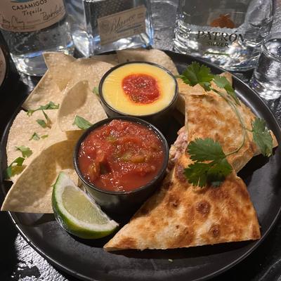 Plate of quesadillas served with tortilla chips and dips.