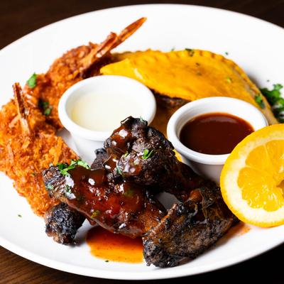 Sampler platter, with chicken wings, beef patties, coconut shrimp, and sauces.