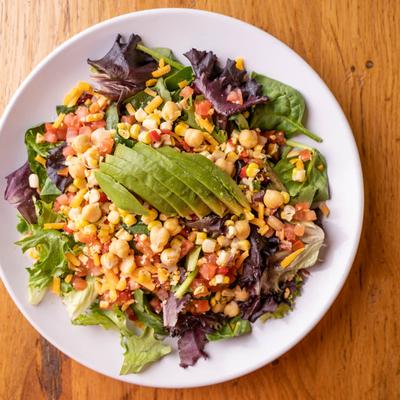 Salad with mixed greens, corn, tomato, onion, and avocado.