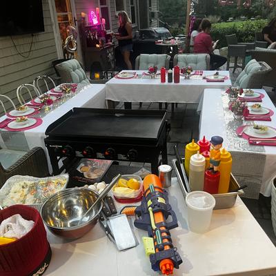 Outdoor event setting with a griddle, set tables, and decorations.