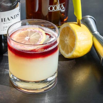 Blood on The Water drink, a wine bottle, jigger, half lemon, and whiskey bottle.