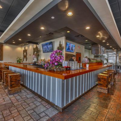 Interior featuring a bar with a wooden counter, TVs, and flower arrangements.