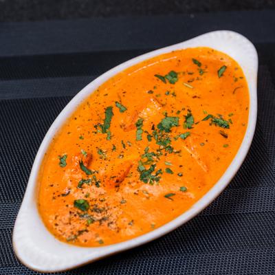 Butter chicken served in a oval dish with herb garnish.
