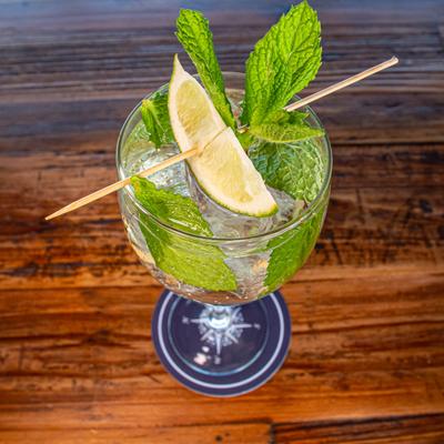 Hugo Spritz cocktail with mint and lime garnish on a wooden table