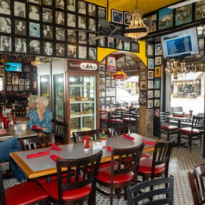 Interior with tables, chairs, photo-covered walls, and a dessert case.