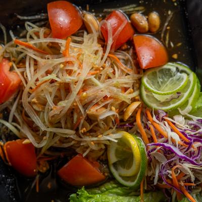 Papaya salad with tomato, shredded carrot and cabbage, lime wheels and lettuce garnish.
