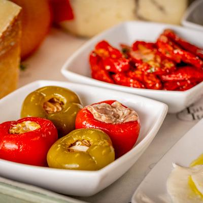 Close up of deli items, cheeses, stuffed peppers, sun dried tomatoes.
