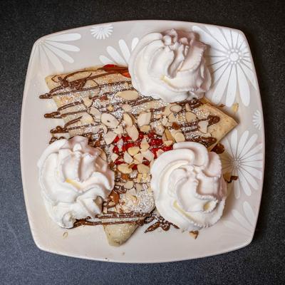 Crepe with Nutella, strawberries, almonds, powdered sugar, and whipped cream.