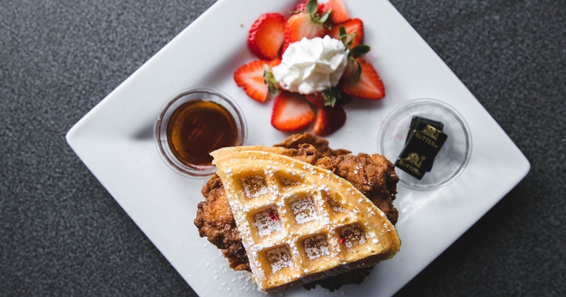 Chicken and waffles with syrup, whipped  cream and strawberries, top view