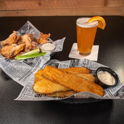 Zucchini planks servd alongside basket of wings and a glass of beer.
