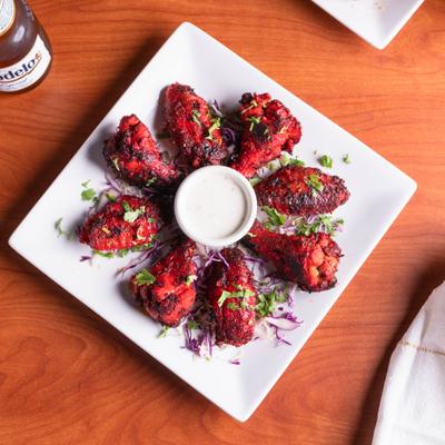 Tandoori wings served with a dipping sauce, overhead view.
