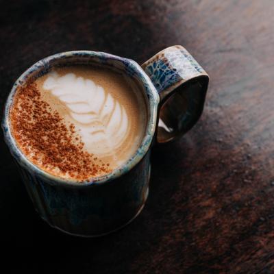 Latte with detailed latte art in a rustic, handmade ceramic mug.